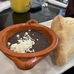 a bowl of black bean soup and a loaf of bread