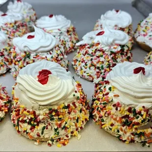 a tray of cupcakes with white frosting and sprinkles