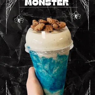 a hand holding a cup of cookie monster milkshake