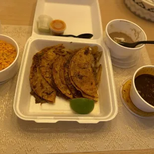 Birria tacos with rice, beans and salsa.