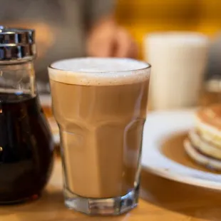 a glass of coffee and a plate of pancakes