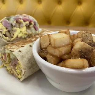 a breakfast burrito and a bowl of potatoes