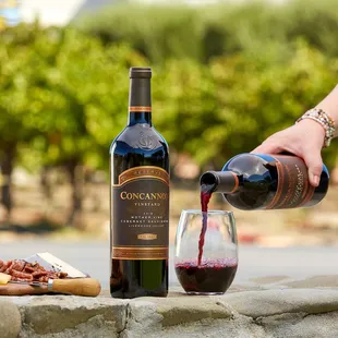 a person pouring red wine into a glass