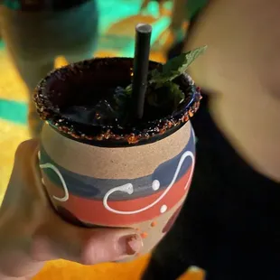 a hand holding a planter with a straw