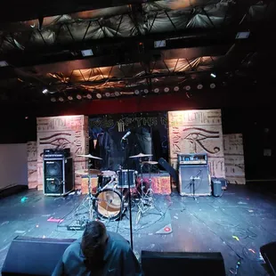 a man sitting on a stage in front of a drum set