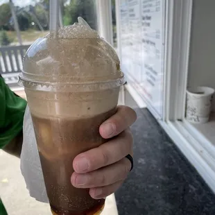 a person holding a cup of iced coffee