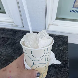 a hand holding a cup of ice cream