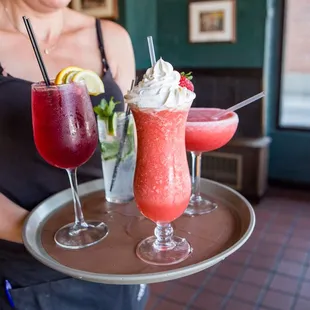 a woman holding a tray with drinks