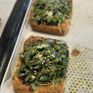 two pieces of bread with greens on top