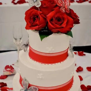 a wedding cake with red roses and butterflies