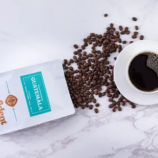 a cup of coffee next to a bag of coffee beans