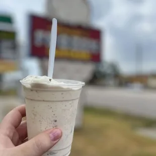 a hand holding a cup of ice cream