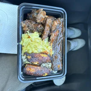 Jerk chicken and jerk ribs, cabbage, rice, plantains, and peas.