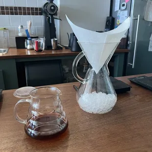 a coffee maker and a glass pitcher on a wooden table