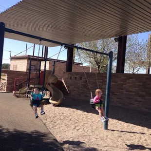 Kid swings (foreground) &amp; playscape (background) with the awning overhead