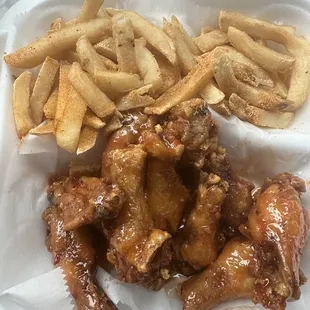 chicken wings and french fries in a styrofoam container