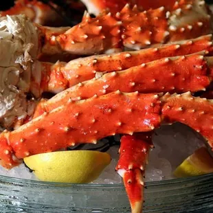 a bowl of crab legs with lemon wedges