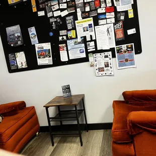 Lounge area with comfy chairs and a posting board with SEVERAL places to help those in need &amp; sign up for programs