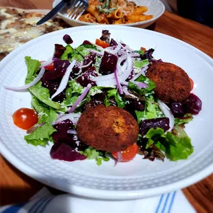 a plate of salad and a plate of meatballs