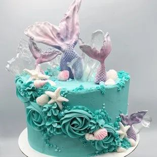 a cake decorated with a mermaid tail and seashells