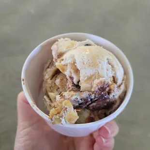 a hand holding a bowl of ice cream