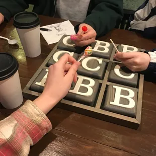 Ticktacktoe game, lollipops, coffee, napkin drawing, coffee table