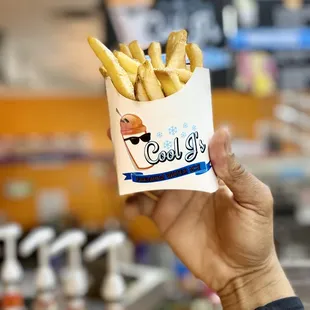 a hand holding a cup of fries