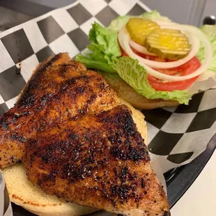 a chicken sandwich with lettuce, tomato, and pickle