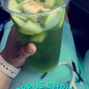 a person holding a cup of green juice