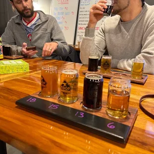 two men sitting at a table with beers