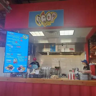 the counter of a restaurant with a menu on the wall