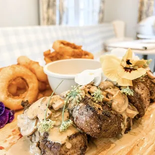 a steak with mushroom sauce and onion rings
