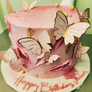a pink birthday cake decorated with butterflies