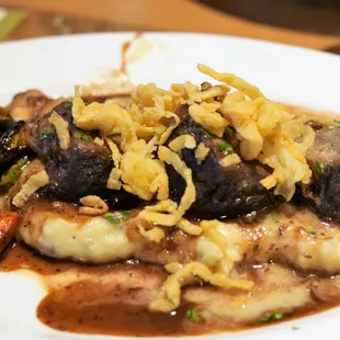 Beef short ribs on mashed potatoes with veggies.