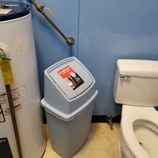 Water heater next to trash can and toilet. Nasty floor.