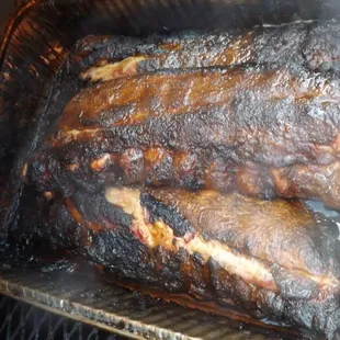 a close up of ribs cooking in a smoker