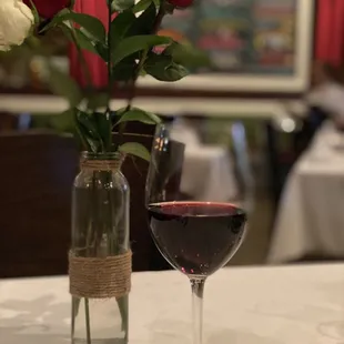 a glass of wine and a vase of roses