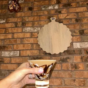 a hand holding a coffee cup in front of a brick wall