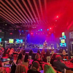 a crowd of people sitting at tables in front of a stage