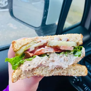 Build your own sandwich. Tuna salad, tomato, lettuce, red onion, and pickles on toasted wheat bread.