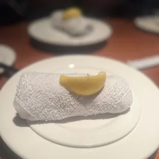 a white plate with a piece of lemon on it