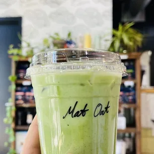 a hand holding a cup of green tea
