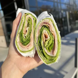 a hand holding a cut in half sandwich