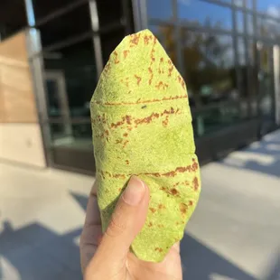 a hand holding a green burrito