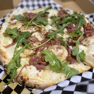 a pizza with mushrooms and arugula
