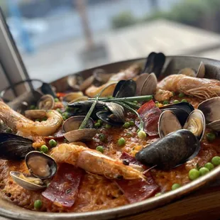 Paella de Tinta BABY CALAMARI A LA PLANCHA, MUSSELS, FIRE ROASTED PIQUILLO PEPPERS, PICKLED GARLIC SCAPES. ATOP BOMBA RICE   $50