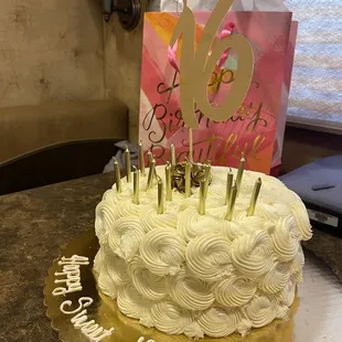 a birthday cake with white frosting and gold icing