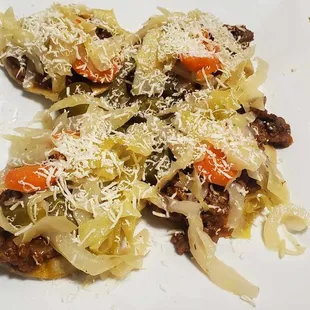 Garnachas Guatemaltecas (Fried tortillas served with ground beef, tomato sauce, cheese, cabbage, onion, carrots, and jalapeños.)