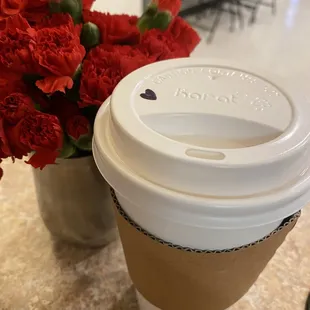 a cup of coffee and a bouquet of red carnations