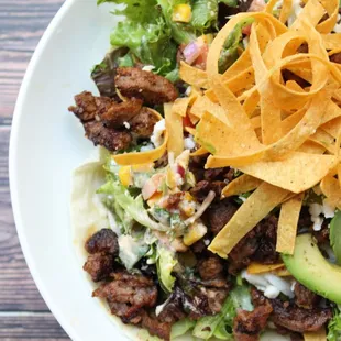 Carne Asada Steak Salad - Mixed greens, avocado, tomato, corn, beans, cilantro, onion, queso fresco, tortilla strips, flour tortilla